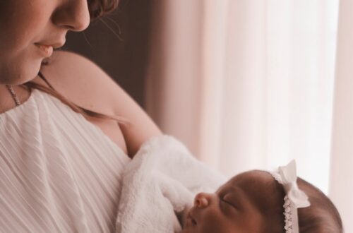 selective focus photography of woman carrying her cute baby