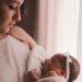selective focus photography of woman carrying her cute baby